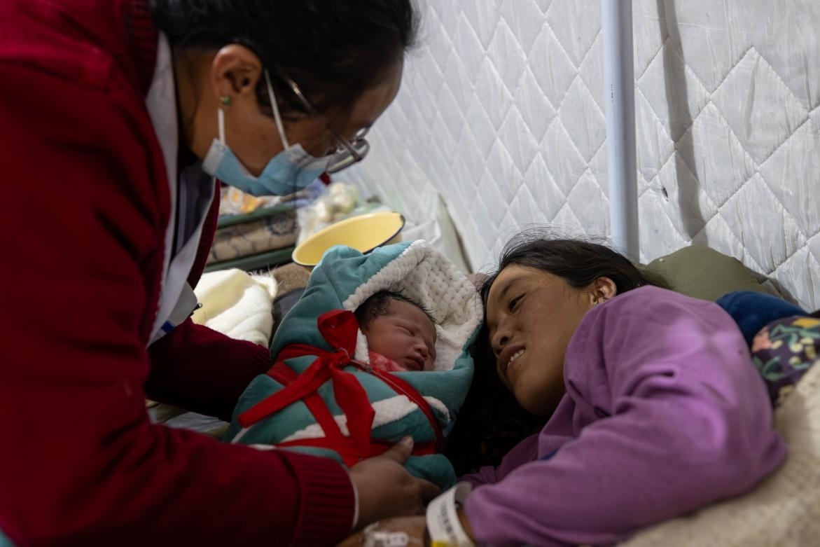 1月10日，定日縣中心醫(yī)院的婦產(chǎn)科醫(yī)生悉心照看一位母親和她懷里的新生兒。人民日報記者張武軍攝