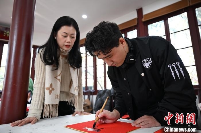 1月20日，外籍留學(xué)生在西泠印社社員李硯指導(dǎo)下寫福。當(dāng)日，來(lái)自巴西、馬來(lái)西亞、加納、哈薩克斯坦的外籍留學(xué)生在浙江杭州西泠印社體驗(yàn)福貼、春聯(lián)和篆刻，感受古老的中國(guó)傳統(tǒng)文化。中新社記者 王剛 攝