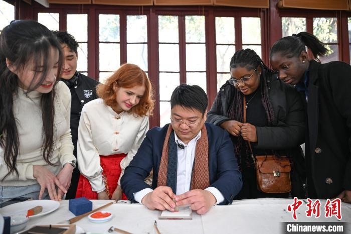 1月20日，篆刻家王臻向外籍留學(xué)生展示篆刻印章。當(dāng)日，來(lái)自巴西、馬來(lái)西亞、加納、哈薩克斯坦的外籍留學(xué)生在浙江杭州西泠印社體驗(yàn)福貼、春聯(lián)和篆刻，感受古老的中國(guó)傳統(tǒng)文化。中新社記者 王剛 攝