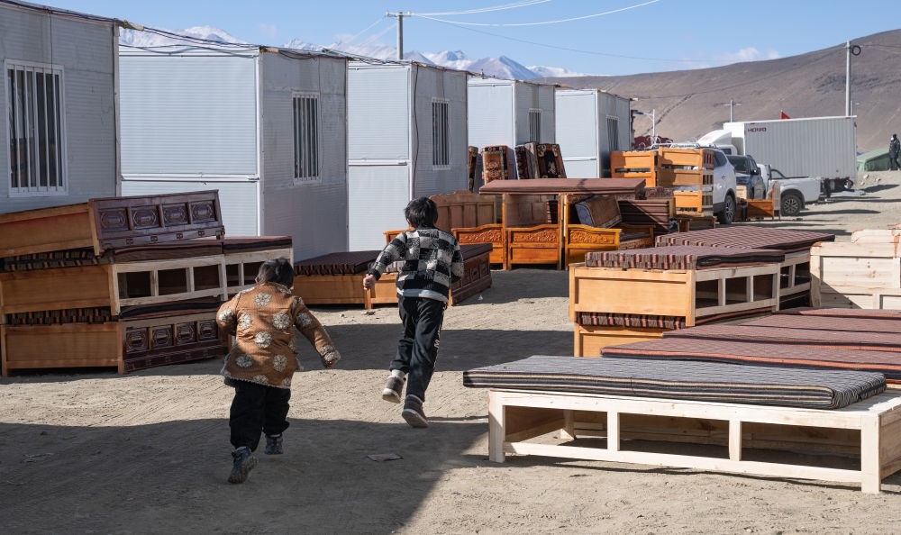 2025年1月13日，在定日縣嘎旦村，兩個(gè)孩子在剛運(yùn)來(lái)的兩排藏床間奔跑。新華社記者丁增尼達(dá) 攝