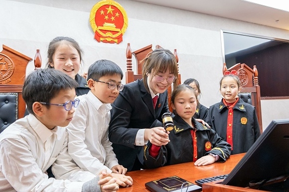 圖①：干警帶同學(xué)們體驗(yàn)敲法槌。