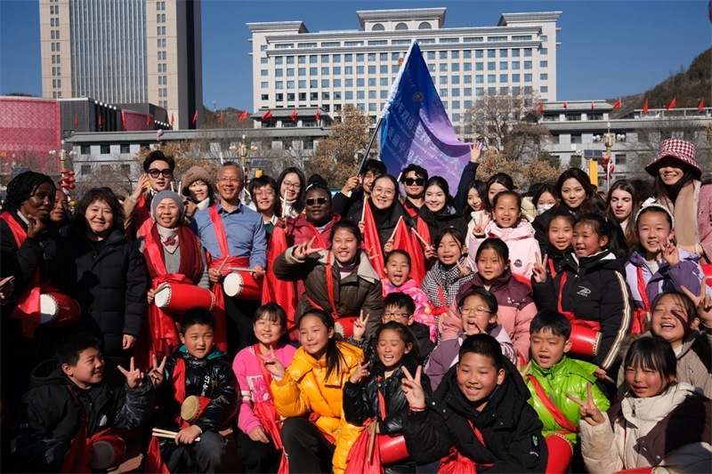 中外青年學(xué)子在安塞文化廣場(chǎng)觀看陜北腰鼓和大秧歌表演后合影留念，大家踏著鼓點(diǎn)共舞，翻飛的紅綢與躍動(dòng)的身影交織，在黃土地廣場(chǎng)上繪出一幅生動(dòng)的陜北民俗互動(dòng)畫(huà)卷