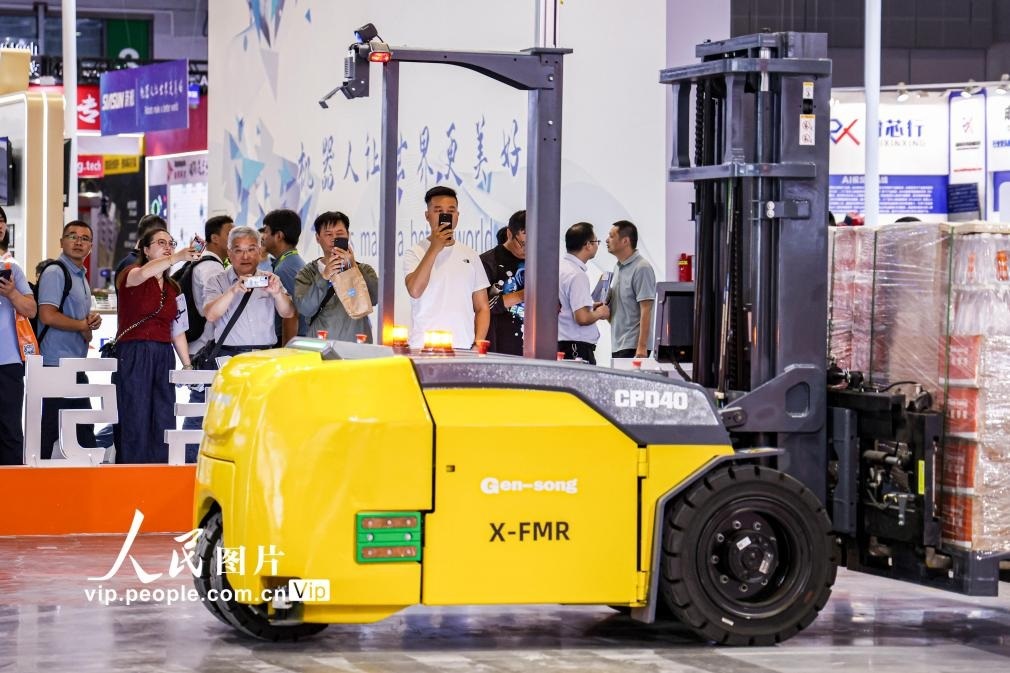 第24屆中國工博會現(xiàn)場，觀眾觀看叉取機(jī)器人作業(yè)演示。王初攝（人民圖片網(wǎng)）