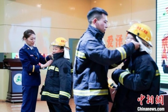 圖為學(xué)生們現(xiàn)場穿戴消防頭盔和戰(zhàn)斗服。中新社記者 趙宇航 攝