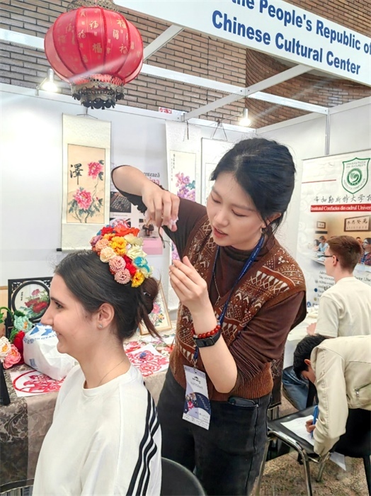 展覽正值羅馬尼亞迎春花節(jié)，國際中文教師志愿者潘婧穎向游客們介紹了國家非物質(zhì)文化遺產(chǎn)——福建泉州的簪花文化。布加勒斯特大學(xué)孔子學(xué)院供圖。