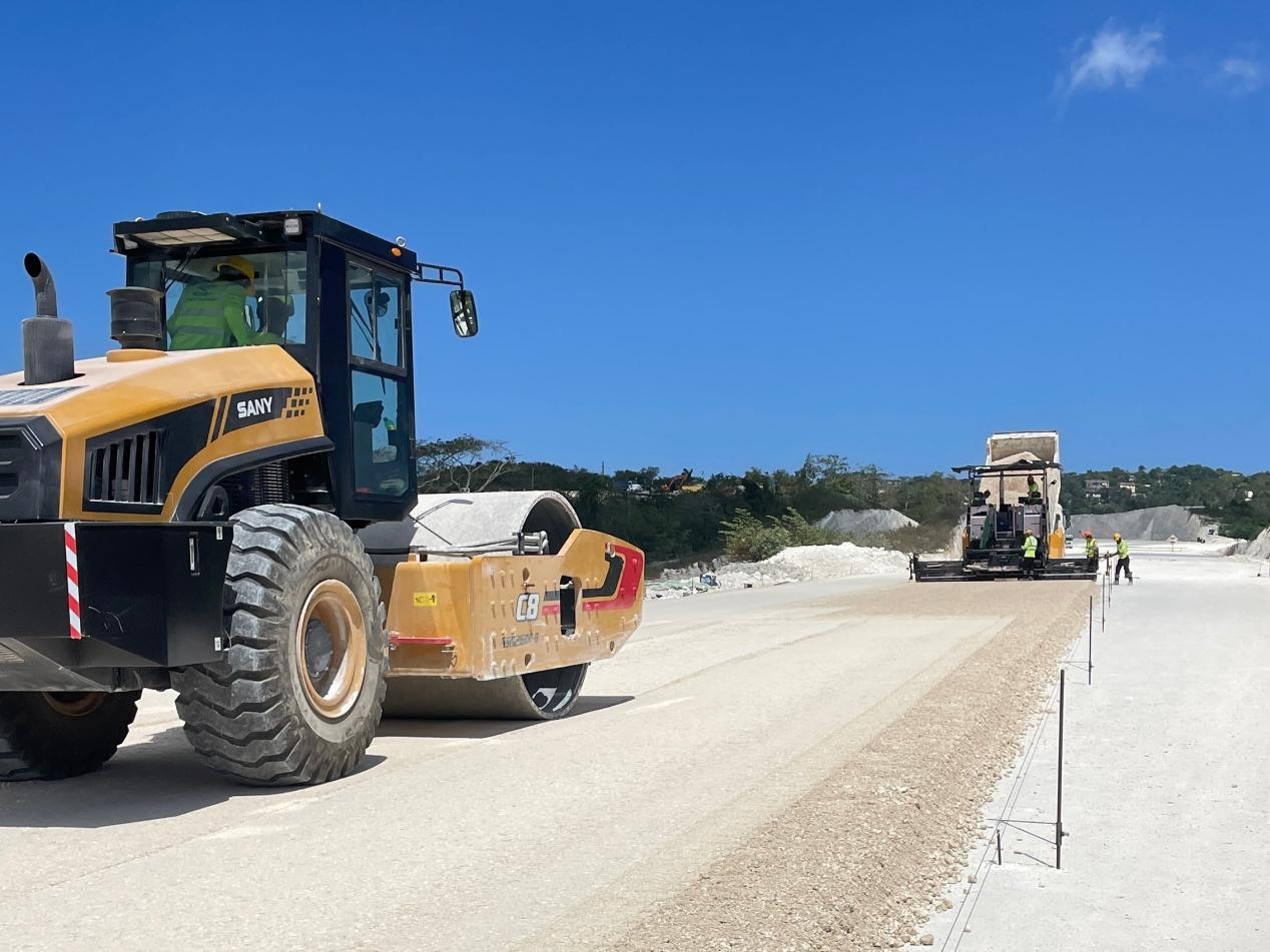 圖為中企承建的牙買加蒙特哥貝繞城路項(xiàng)目基層試驗(yàn)段正在進(jìn)行攤鋪和碾壓施工，相關(guān)施工工作已于日前順利完成。中國(guó)港灣美洲區(qū)域公司供圖