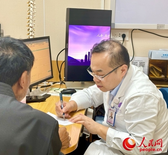 路桂軍接診時(shí)為患者寫下用藥提示。人民網(wǎng)記者 金慧慧攝