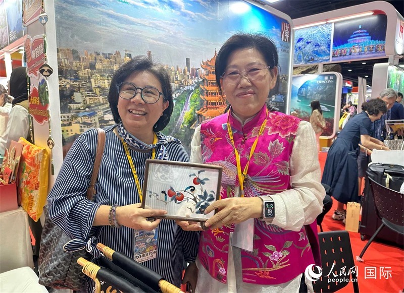 中國“大冶刺繡”傳承人劉小紅（右）參加泰國國際旅游展，向觀眾介紹中國非遺刺繡針法。人民網(wǎng)記者 簡承淵攝
