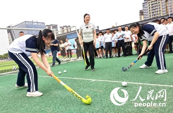 陳朝霞（中）指導學生體驗曲棍球。 人民網記者 楊磊攝