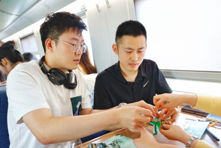 G232次旅客親手制作端午荷包和五彩繩。王磊攝