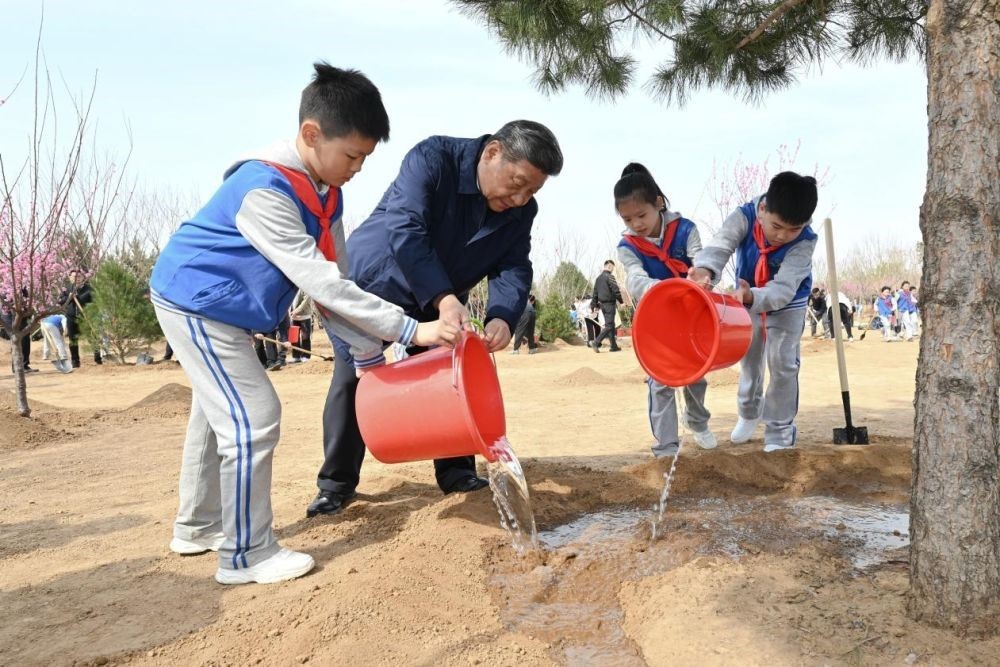 2025年4月3日，習(xí)近平總書記等來到北京市豐臺區(qū)永定河畔參加首都義務(wù)植樹活動。這是習(xí)近平總書記同少先隊員一起給剛栽下的樹苗澆水。新華社記者 謝環(huán)馳 攝